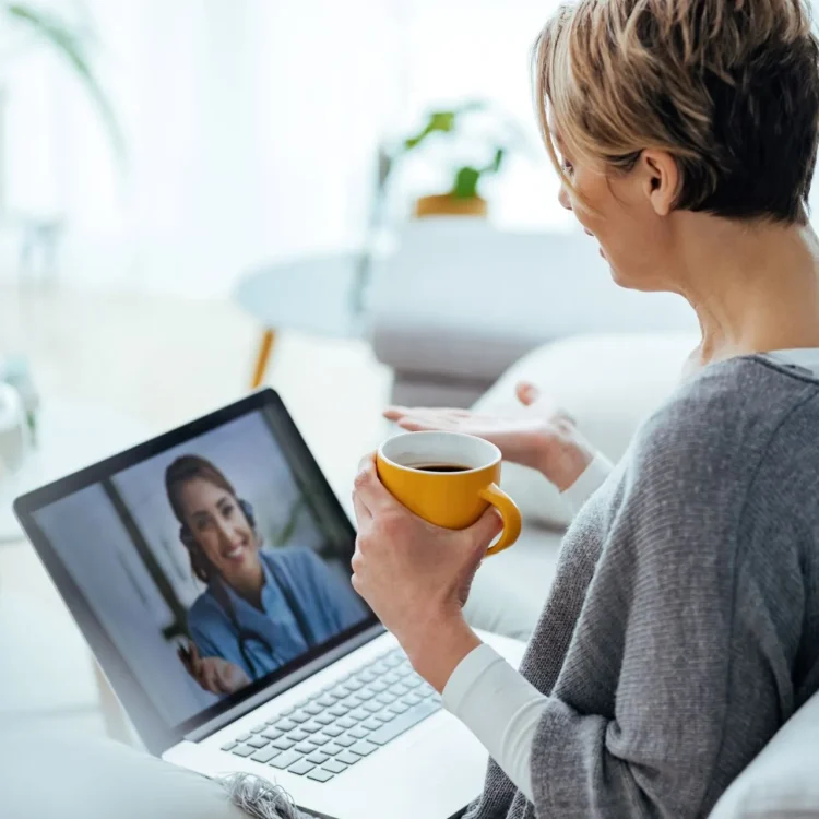 woman drinking coffee on her couch while on a video call