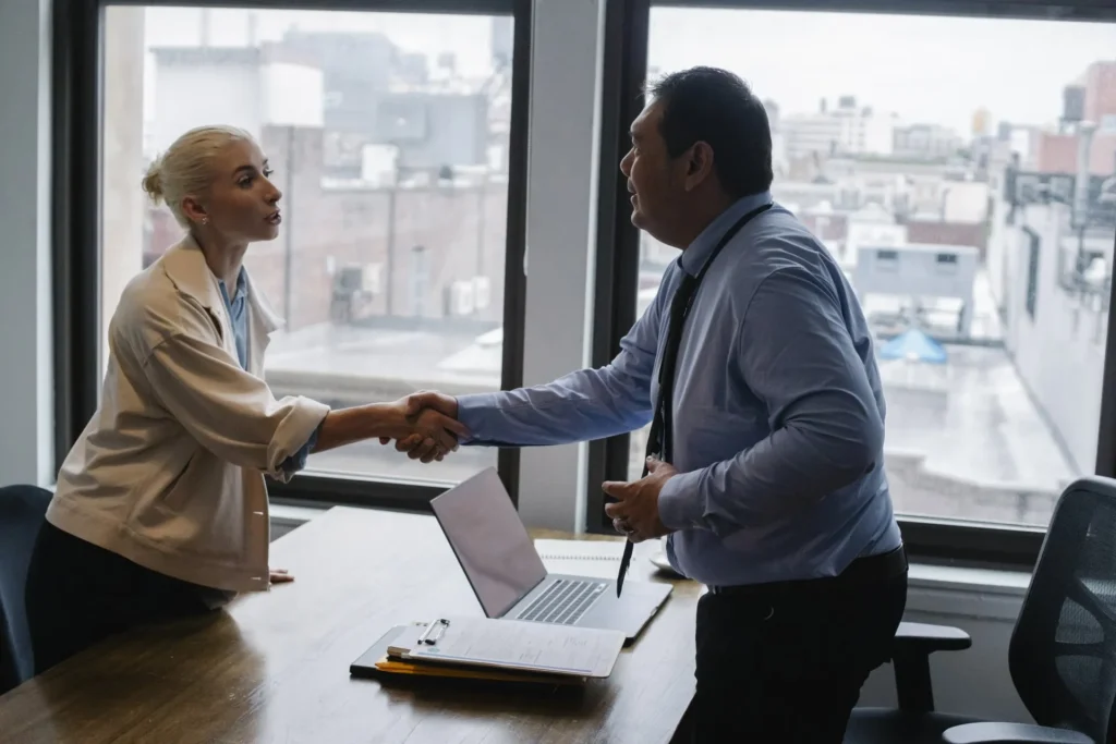 man & woman shaking hands over a desk